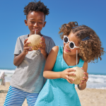 Crianças com roupas moda praia tomando coco.