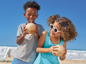 Crianças com roupas moda praia tomando coco.