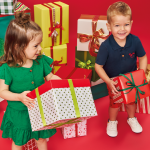 Crianças usando look de Natal e segurando caixas de presente