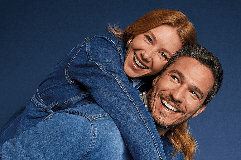 Casal sorridente usando looks jeans em clima descontraído, representando conexão e principais dúvidas sobre jeans no dia a dia