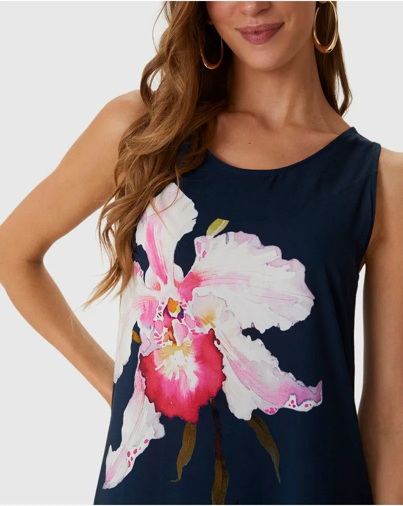 Modelo branca de cabelos soltos veste vestido azul marinho da marca Malwee, com estampa grande da flor hibisco.