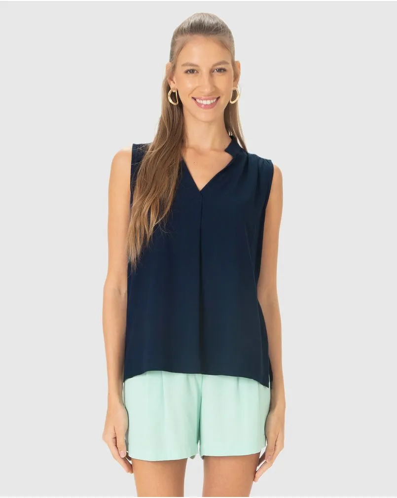 Modelo branca com rabo de cavalo veste blusa sem mangas com botões, na cor azul marinho, da marca Malwee.