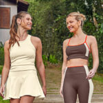 Modelos vestem conjuntos de academia malwee active, com regata e shorts-saia off white e conjunto de top e legging em marrom.